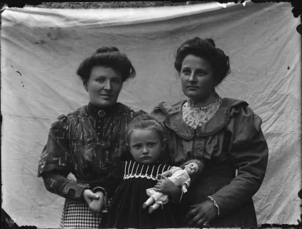 Val Brembana. Ritratto di due donne e di una bambina con bambola in braccio