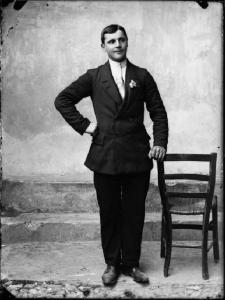 Piazza Brembana. Ritratto di un uomo in giacca e cravatta appoggiato a una sedia
