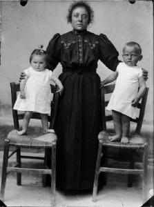 Val Brembana. Ritratto di una madre con i figli piccoli in piedi su sedie