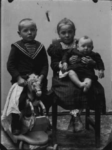 Val Brembana. Ritratto di tre bambini con cavallino a dondolo