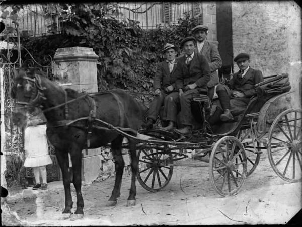 Piazza Brembana. Calesse con quattro uomini trainato da un cavallo davanti a casa Goglio in via Umberto I (ora via Belotti)