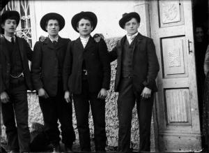 Val Brembana. Ritratto di quattro giovani uomini davanti alla porta di una casa