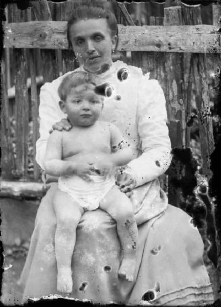 Val Brembana. Ritratto di donna con bambino sulle ginocchia e staccionata sullo sfondo