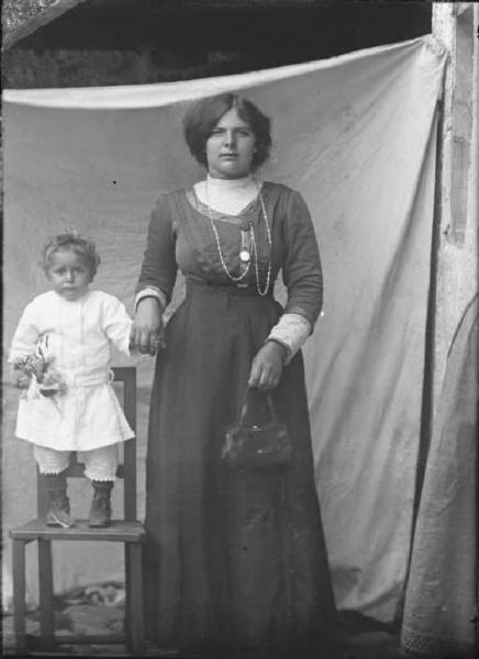 Val Brembana. Ritratto di donna con bambino in piedi su una sedia