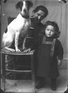 Piazza Brembana. Ritratto di donna con bambina e cane su una sedia