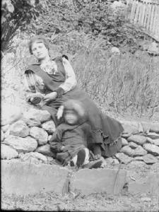 Val Brembana. Ritratto di donna e bambina sedute su un muretto in un campo