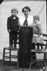 Val Brembana. Ritratto di donna con due bambini in piedi su sedie