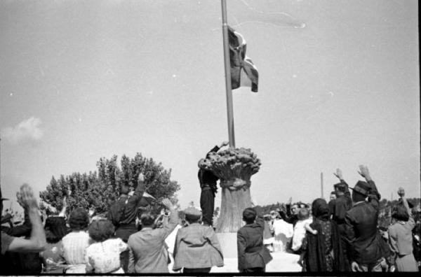 Sannazzaro de' Burgondi - Gruppo di persone disposte attorno al monumento raffigurante un fascio di spighe - Bandiera italiana