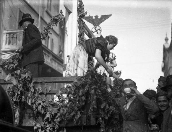 Broni - VIII Festa dell'uva - Carro folcloristico con il fascio littorio e lo stemma della Germania nazista (Terzo Reich) - Giovane donna protesa sulla folla