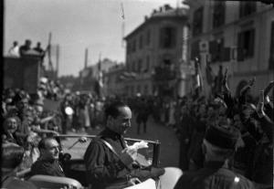 Mortara - Achille Starace in piedi nell'autovettura - Gruppo di fascisti in divisa - Folla gioiosa