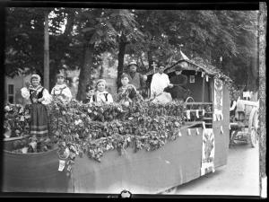 Ritratto di gruppo - Giovani donne in abiti tradizionali, un Balilla, un uomo con cappello, uno vestito di bianco ed uno da sacerdote sul carro addobbato con tralci di vite, grappoli d'uva - Pavia - 3° Festa nazionale dell'uva