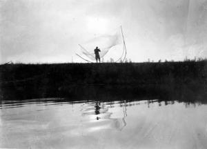 Pescatore con le reti sulla riva del fiume