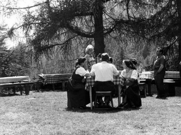 Valligiani. Donne in costume con altre persone sedute ai tavoli de "La Raviolata" organizzata al rifugio Roccoli Lorla dal C.A.I. Sezione di Dervio.