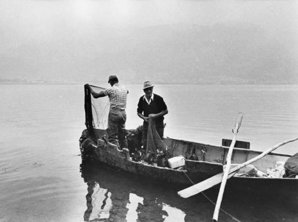 Pescatori su una barca con reti e pescato.