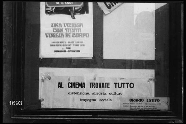 Bacheca murale con manifesto del film "Una viziosa con tanta voglia in corpo"; locandina con scritta "Al cinema trovate tutto (...)"; cartello con "Orario estivo".