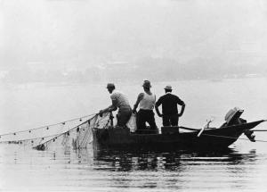 Pescatori su una barca mentre alzano la rete.
