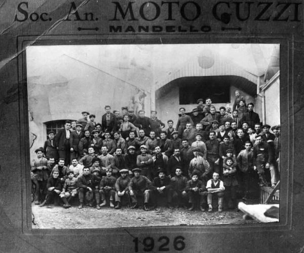 Gruppo di operai della "Moto Guzzi" in posa all'esterno della fabbrica.