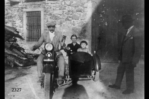 Angelo Nardi in moto; sul sidecar la moglie Elisa e la figlia Lucia. Posa di gruppo in esterno;  in basso al centro l'ombra del fotografo.