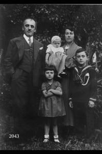 Vittoria Angiolini con Mansueto Comana e figli. Posa a  figura intera in un giardino.