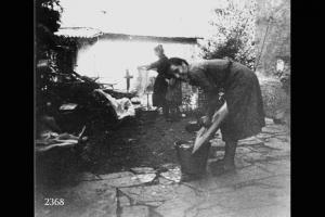 Concetta e Maria Locatelli. Una donna lava in un secchio, l'altra stende su una catasta di legna.