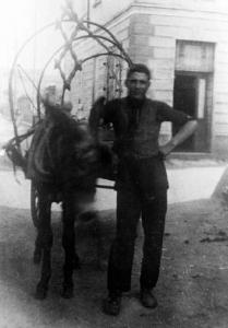 Emilio Maconi, ambulante di ferramenta, posa in esterno con un carretto trainato da un asino.