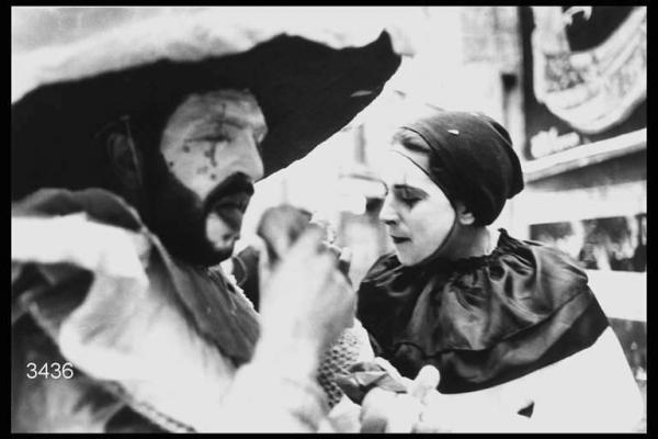 Carnevale ambrosiano. Un uomo e una donna in maschera; l'uomo, in primo piano, sta mangiando.