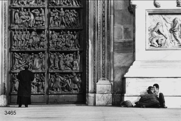 Carnevale ambrosiano. Coppia seduta di fianco a un portale del Duomo.