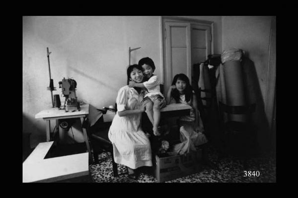 Laboratorio di pelletteria cinese. Donna con bambino e ragazzina. Immigrazione cinese.