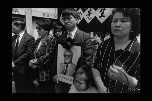 Funerale cinese. In primo piano, ragazzo che porta il ritratto fotografico dell'estinto. Immigrazione cinese.