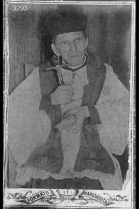Don Giovanni Codalli - Sacerdote seduto con crocefisso e bibbia.