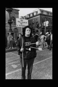 Milano. Uomo col viso truccato sostiene un cartello con la scritta " W Reagan W il governo".