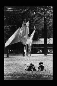 Milano. Parco Sempione. Festa dell'Unità: due ragazze sdraiate sull'erba; sullo sfondo bandiere mosse dal vento.