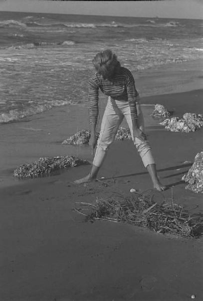 Rodi Garganico. Spiaggia. L'attrice Melina Mercouri disegna sulla sabbia con un ramo