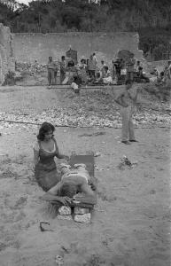Rodi Garganico. Spiaggia. Set del film "La legge", diretto da Jules Dassin. Gina Lollobrigida, seduta di fianco al regista, ha terminato il massaggio