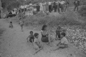 Rodi Garganico. Spiaggia. Set del film "La legge", diretto da Jules Dassin. Gina Lollobrigida, seduta sulla sabbia, gioca con alcuni bambini