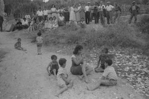 Rodi Garganico. Spiaggia. Set del film "La legge", diretto da Jules Dassin. Gina Lollobrigida, seduta sulla sabbia, gioca con alcuni bambini