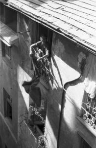 Genova. Veduta sui tetti della città. Una donna, alla finestra, sbatte una coperta