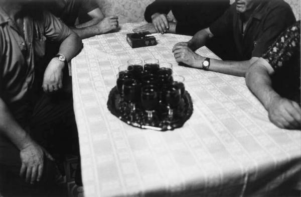 Canto popolare, gruppo di Santa Croce. Canto in osteria: uomini seduti intorno a un tavolo con bicchieri di vino.