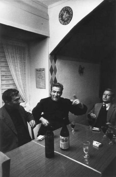 Canto popolare, gruppo di Santa Croce.  Canto in osteria: tre uomini intorno a un tavolo con bicchieri di vino.