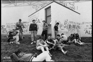 Gruppo di ragazzi di fianco ad un edificio pieno di scritte.