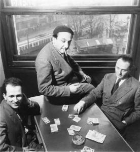 Tre uomini intorno ad un tavolo giocano a carte.