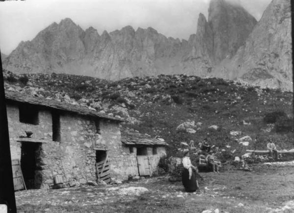 Cascina bassa Campelli - Montanari e giovane donna accanto alla cascina;  sullo sfondo cime montuose.