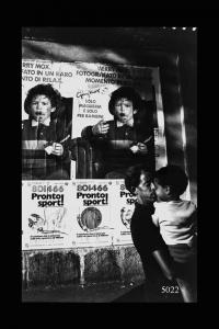 Eritrei a Milano. Padre e figlio in una via della città.sullo sfondo manifesti  pubblicitari.