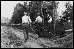Il lavoro dei cordai di Castelponzone. I due cordai, camminando lentamente, ottengono la corda utilizzando un apposito strumento chiamato "masol" che intreccia i legnoli (gli elementi che, ritorti, formano la corda).