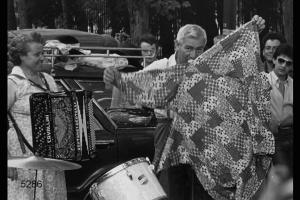 Spettacolo di cantastorie pavesi in Piazza del Cannone a Milano. I cantastorie Vincenzina Cavallini e Angelo Cavallini  in una fase dello spettacolo. Angelo Cavallini mostra una giacca da clown prima di indossarla.