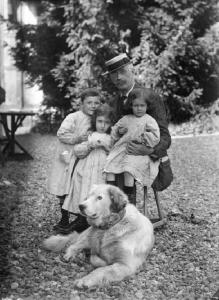 Gruppo a Vilminore - Posa in esterno, in giardino. - Uomo anziano con paglietta accanto a tre bambini. - Ai suoi piedi un  cane.