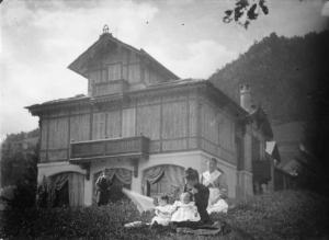Gruppo davanti alla casa di Vilminore. La balia, una giovane donna con due bambini piccoli e sullo sfondo  un uomo, nel prato davanti a una villa.