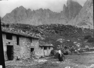 Cascina bassa Campelli - Montanari e giovane donna accanto alla cascina;  sullo sfondo cime montuose.