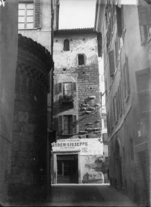 Torre di Ercole e resto della chiesa di San Marco a Brescia. Inquadratura della fronte della torre del Quattrocento adibita ad abitazione e  negozio (pizzicheria)  sulla sinistra abside romanica.