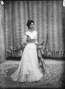 Signora Mary Feraldi Benedetti. Giovane donna in elegante abito chiaro e ombrellino in posa a figura intera all'esterno.